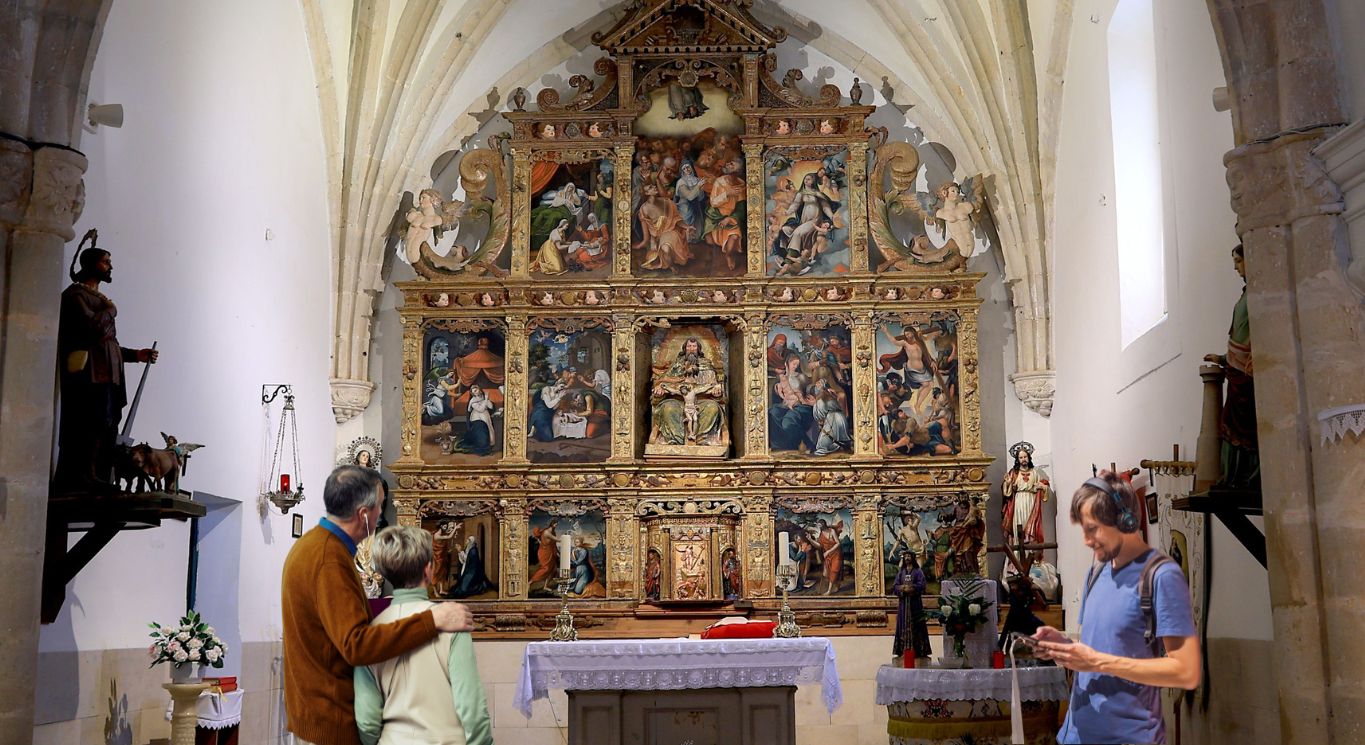 Simulación realizada con IA de un grupo de personas escuchando la adioguía del retablo de Yugueros